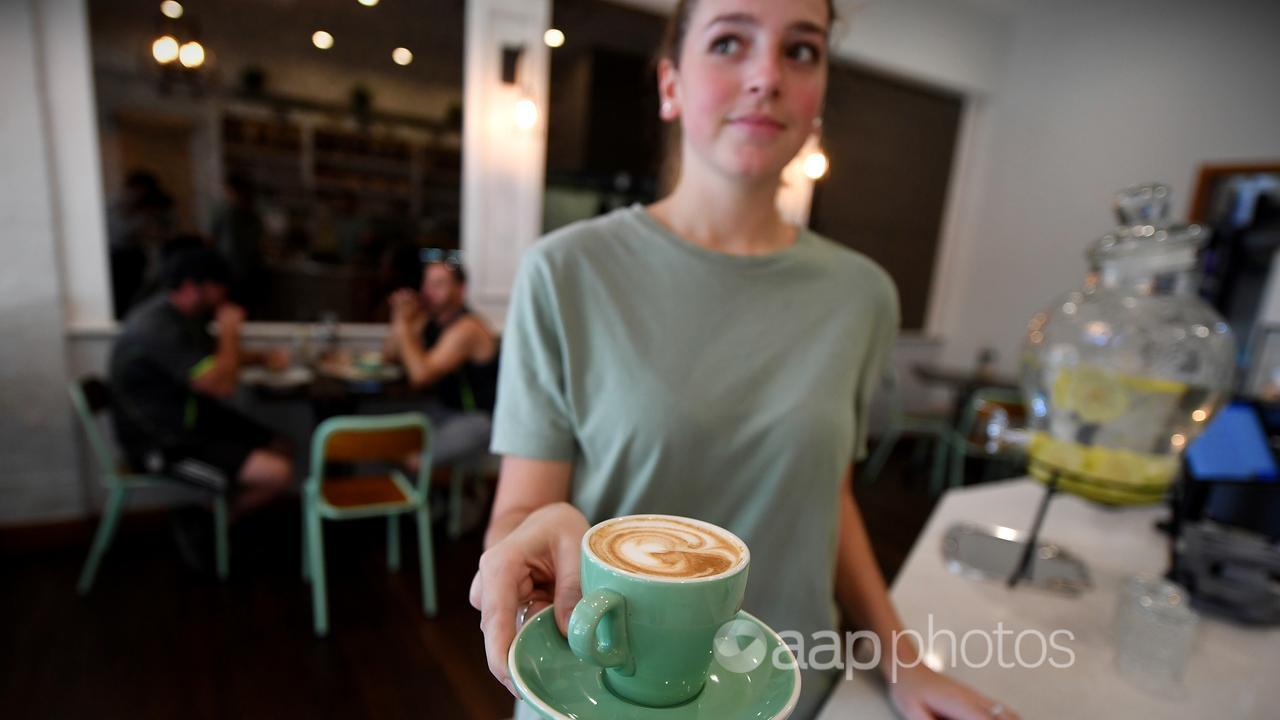 A waitress is seen holding a coffee at a cafe in Canberra